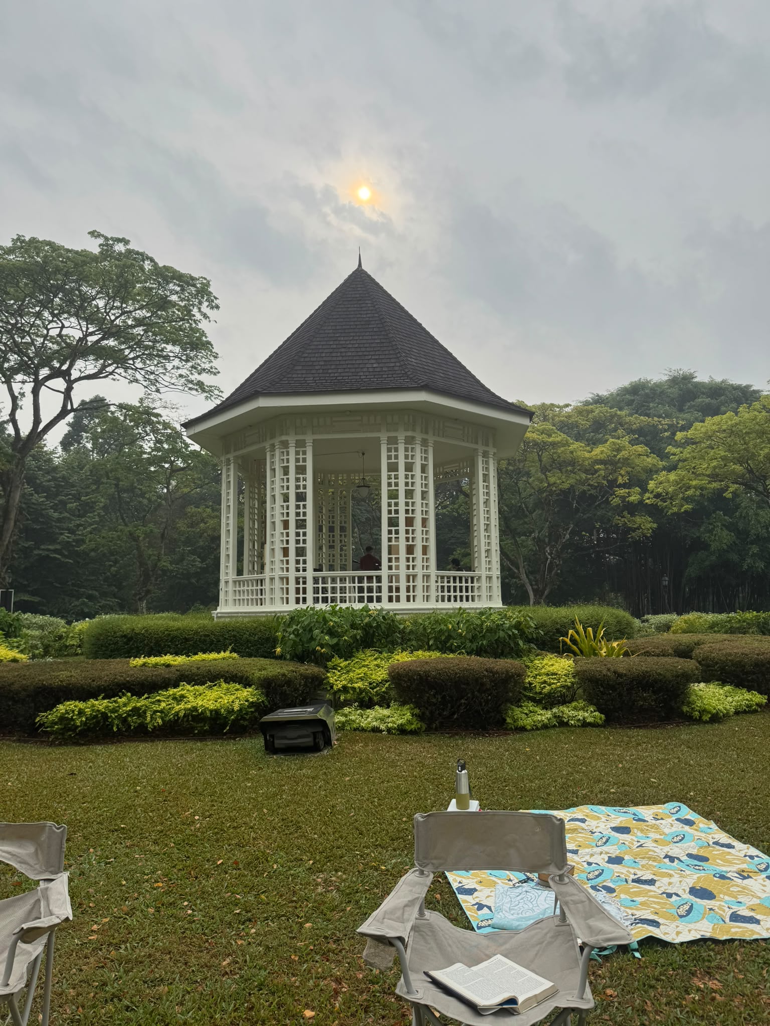 A reading chair and picnic blanket facing the white Botanic Gardens Bandstand