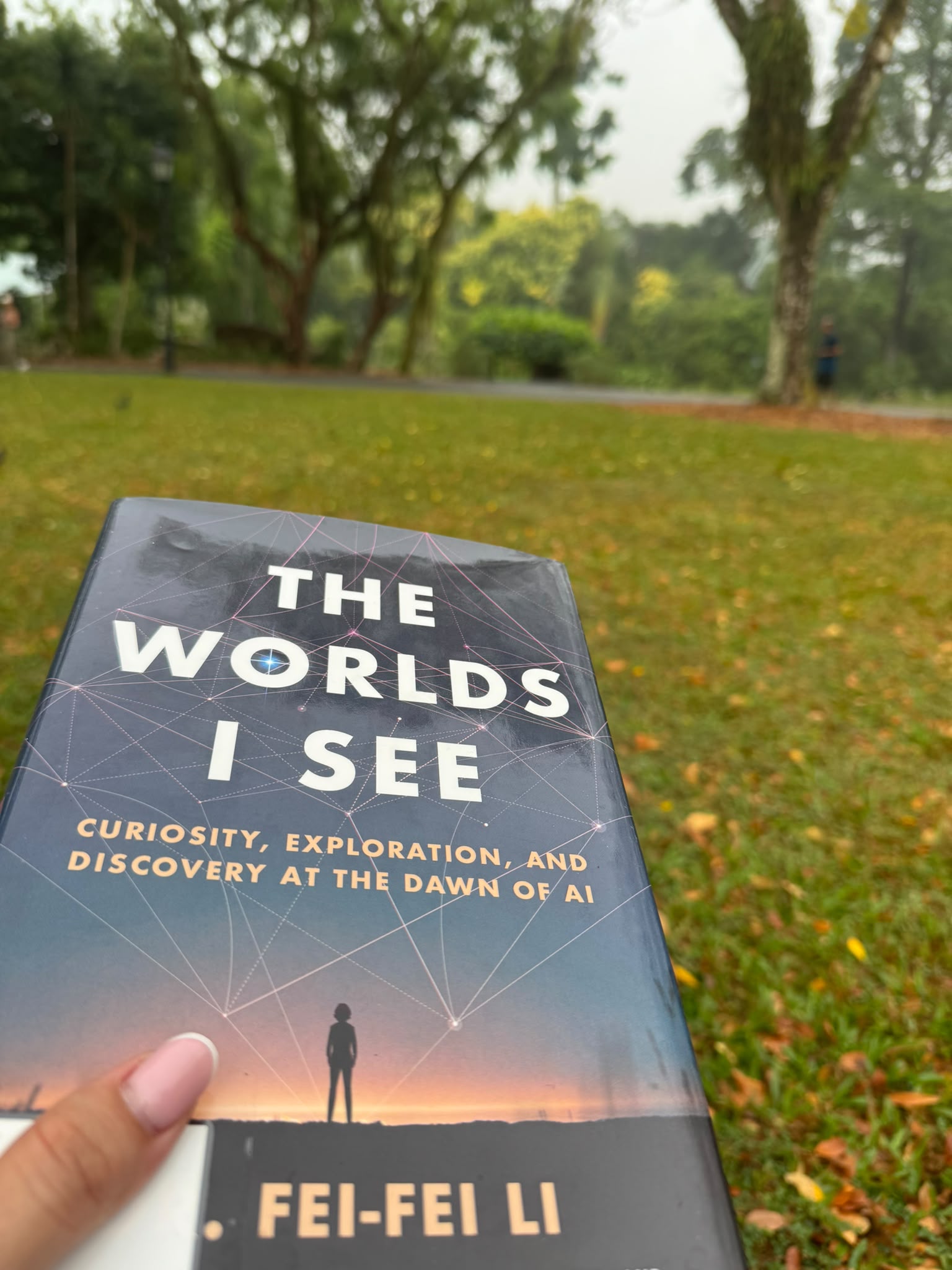 The Worlds I See held up against the green garden lawn